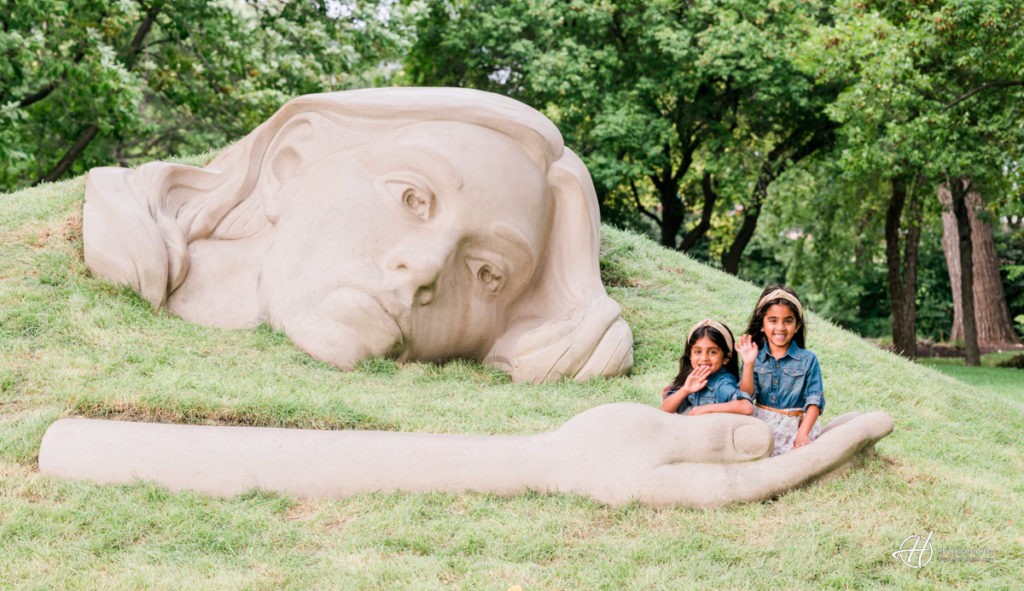 Giana and Zadie playing in the palm of a giant statue.