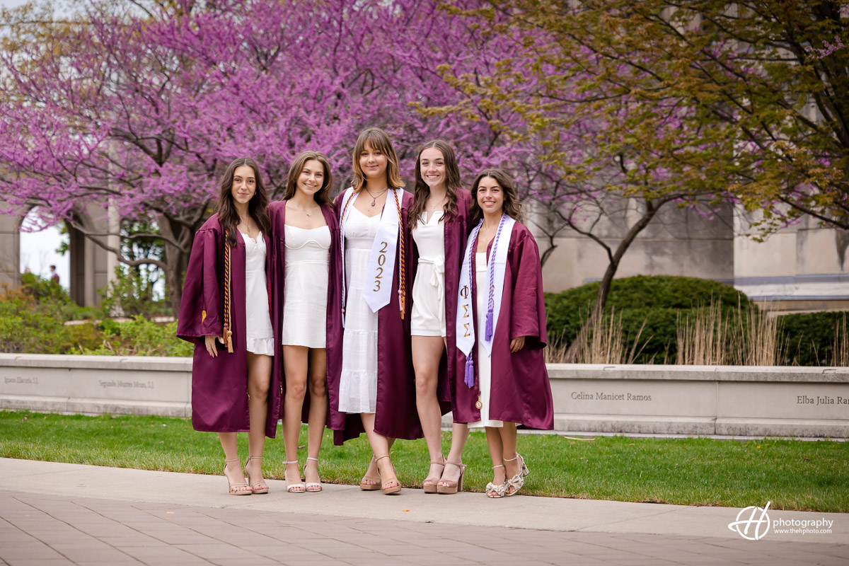 Nature's backdrop for cherished memories: Loyola University Chicago seniors stand united in front of bloomed trees, capturing the essence of friendship and growth amidst the vibrant beauty of the campus