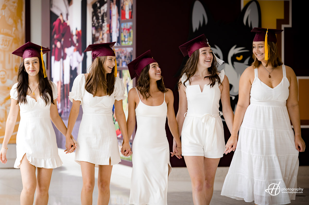 Bound by friendship and lifelong connections: Loyola University Chicago seniors walk hand in hand, engaged in lively conversation, symbolizing their enduring camaraderie and support as they navigate the path ahead with unwavering unity.