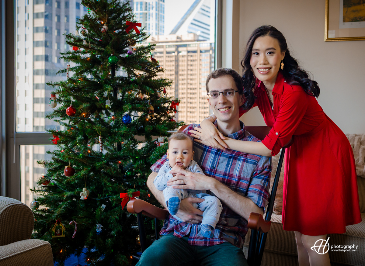 Lisa, Perry and their baby creating a Christmas Card with the tree and Chicago buildings in background. 