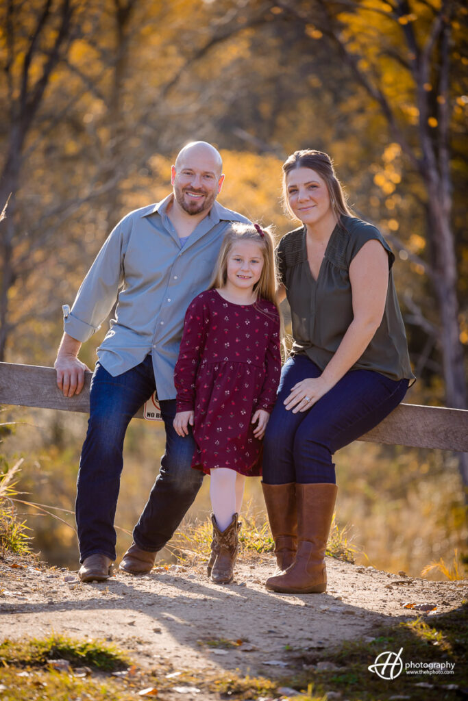 Set against the natural beauty of Reecewoods Forest Preserve, Derek, Laura, and Sadie form a united front, surrounded by the serene ambiance of nature. The play of dappled sunlight and the lush greenery create a timeless backdrop for this family portrait.