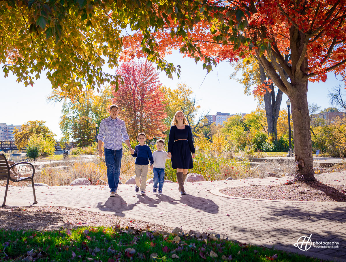 The Woodcox family strikes a heartwarming pose in Walton Island Park, Elgin, amidst the captivating colors of fall. Against the backdrop of autumn foliage, their unity and joy radiate, creating a timeless family portrait capturing the essence of the season's beauty.