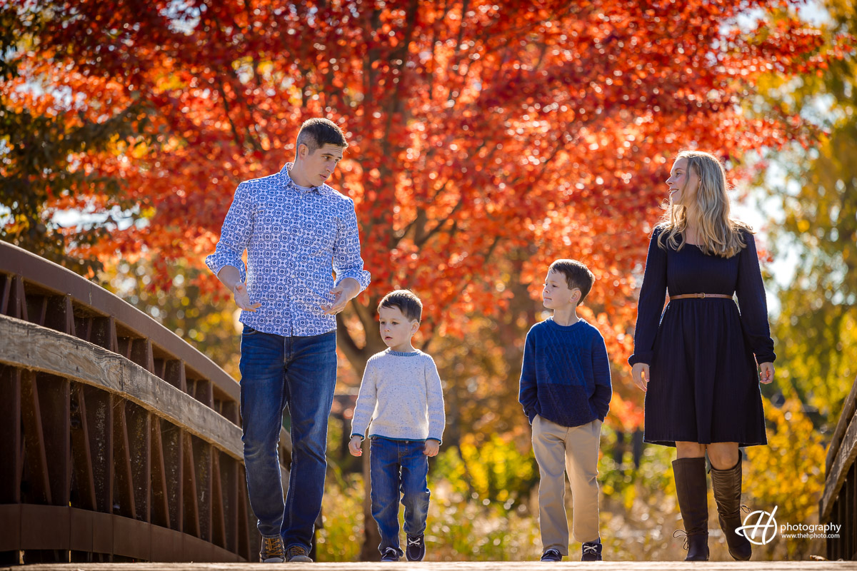 "As the Woodcox family strolls along the bridge at Walton Island Park, Elgin, the father passionately explains while I seize a candid shot. The genuine moment unfolds, capturing the essence of familial connection and shared stories against the scenic backdrop of the park's serene surroundings."