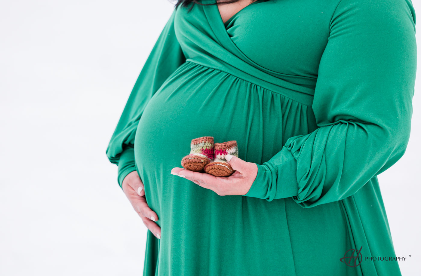 baby shoes agains the belly and green maternity dress