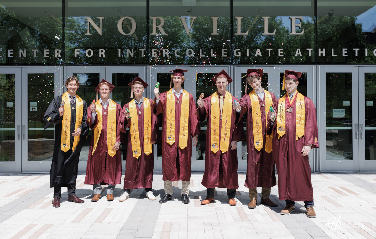 **Alt Text:** A group of smiling graduates in their caps and gowns, posing together with a volleyball, symbolizing their shared experiences and friendship formed during their years playing volleyball at Loyola Chicago University.