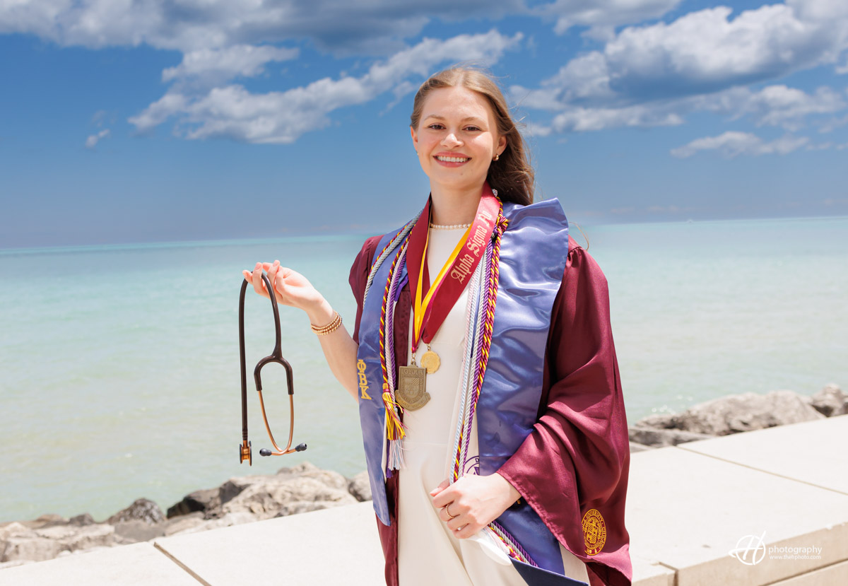 Kate posing by Lake Michigan with her stethoscope showing that she graduates in medical field