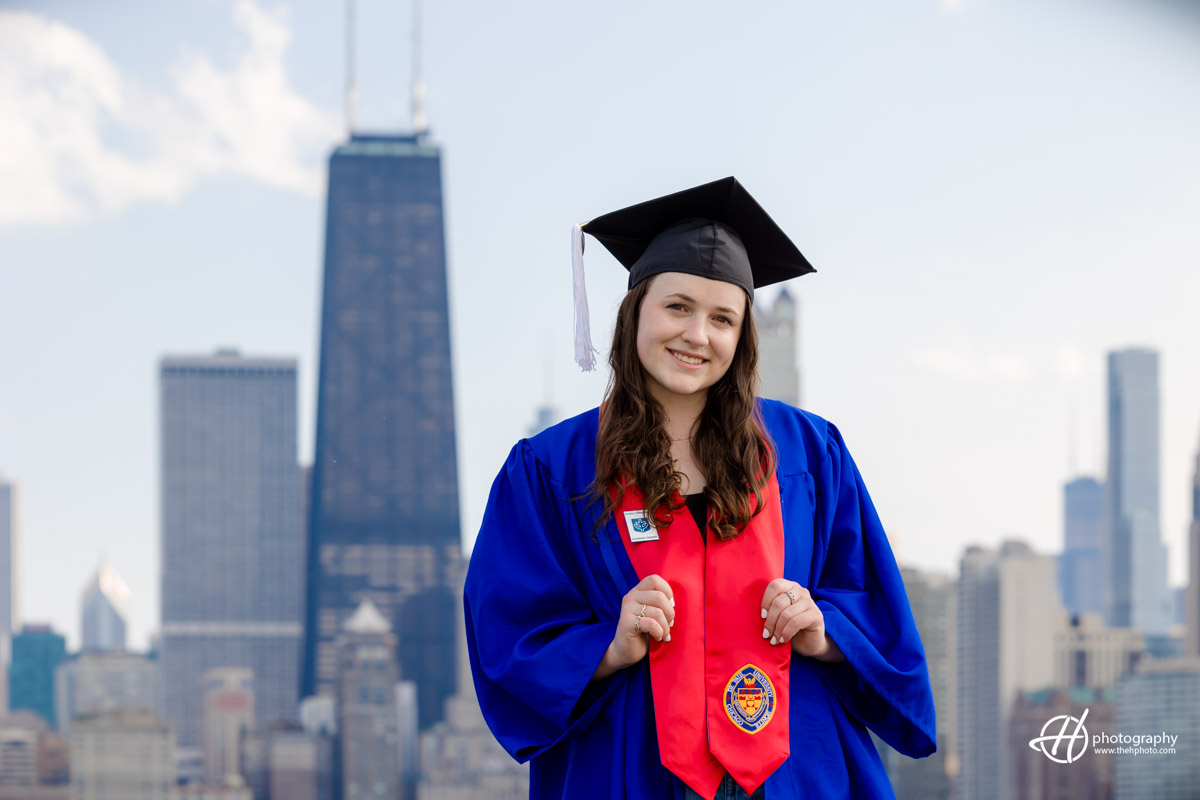 Portrait of Amelia in her graduation robe from DePaul university. Chicago skyline appears in the background.