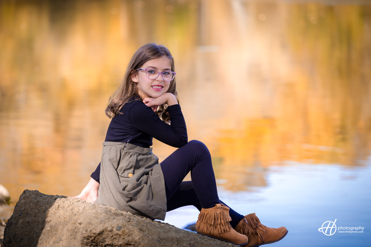 Gabriela portrait agains the water mirroring the golden trees in the morning 