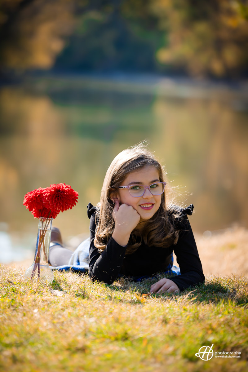 Portrait of child sitting on the grass and having red flowers 